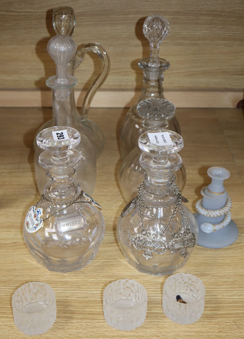 A pair of cut glass decanters, three other decanters, a claret jug and other glassware together with various labels, one silver whisky